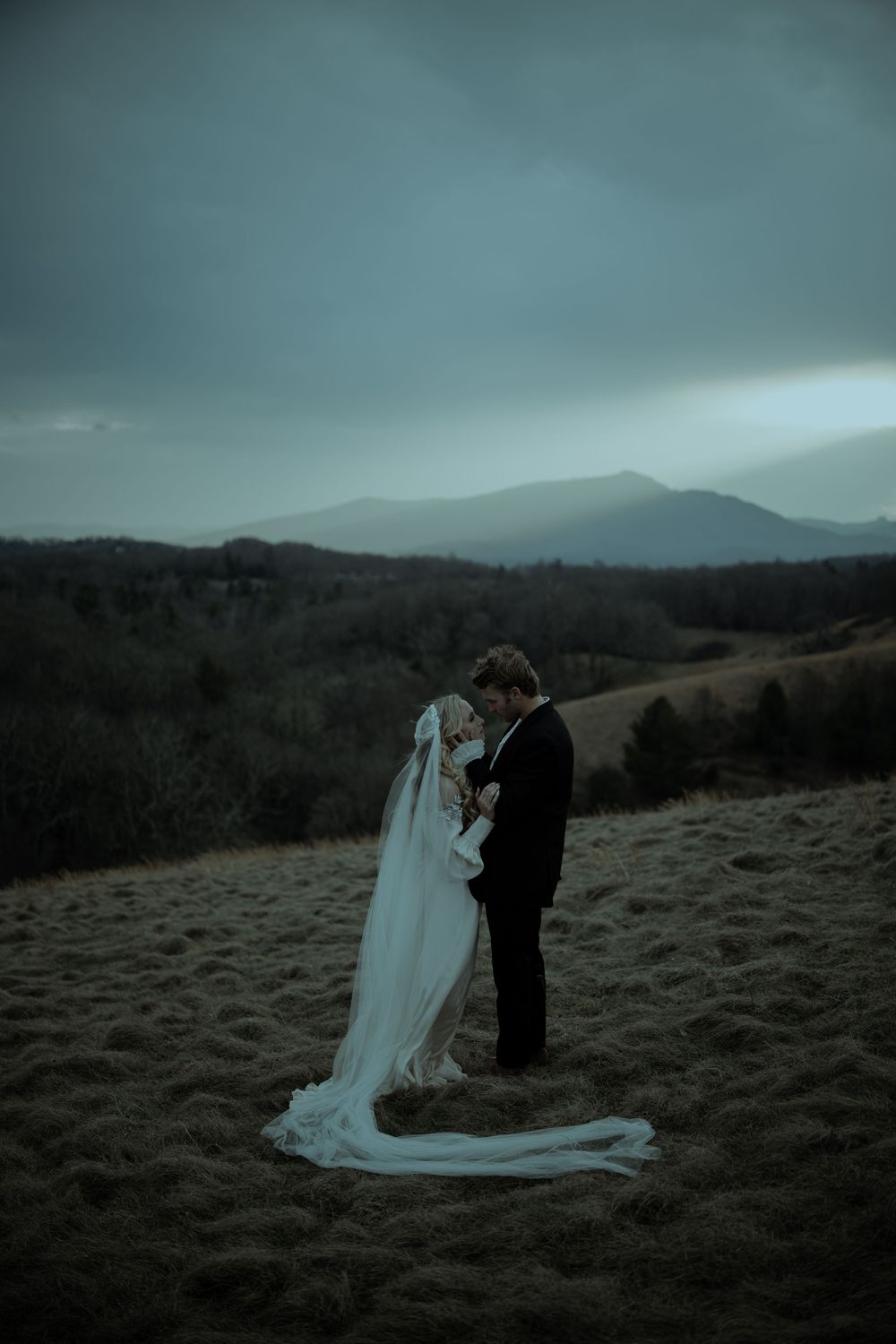 A couple shares an intimate moment during their moody mountain wedding photoshoot at dusk.