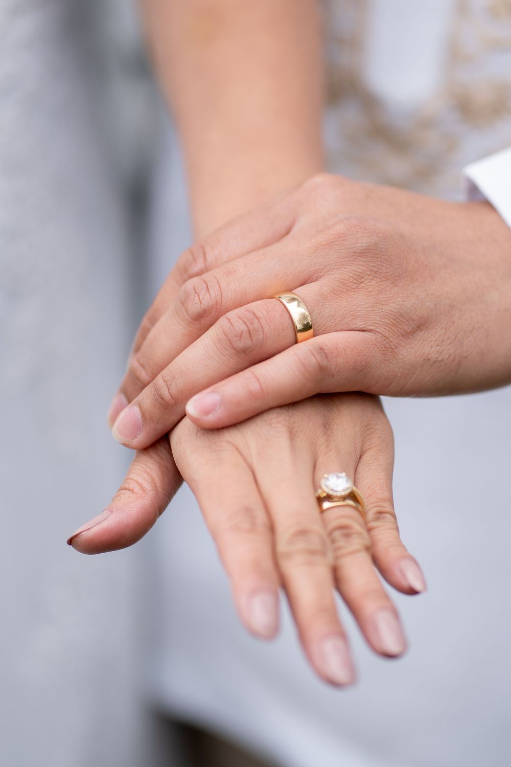 Two hands with gold wedding rings touching gently, symbolizing marriage and commitment.
