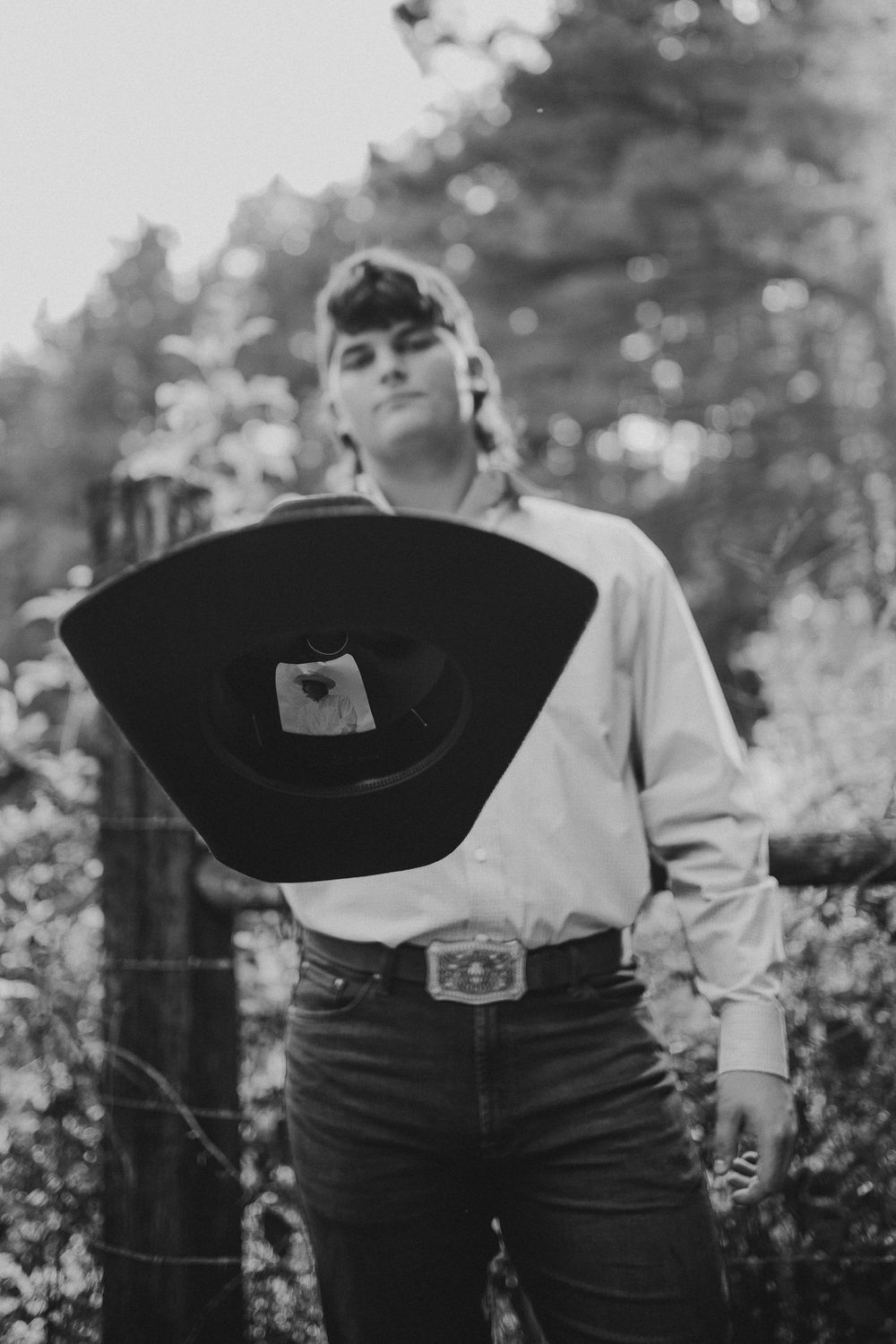 A close-up detail shot of vintage-style denim jeans with a belt buckle in black and white photography.