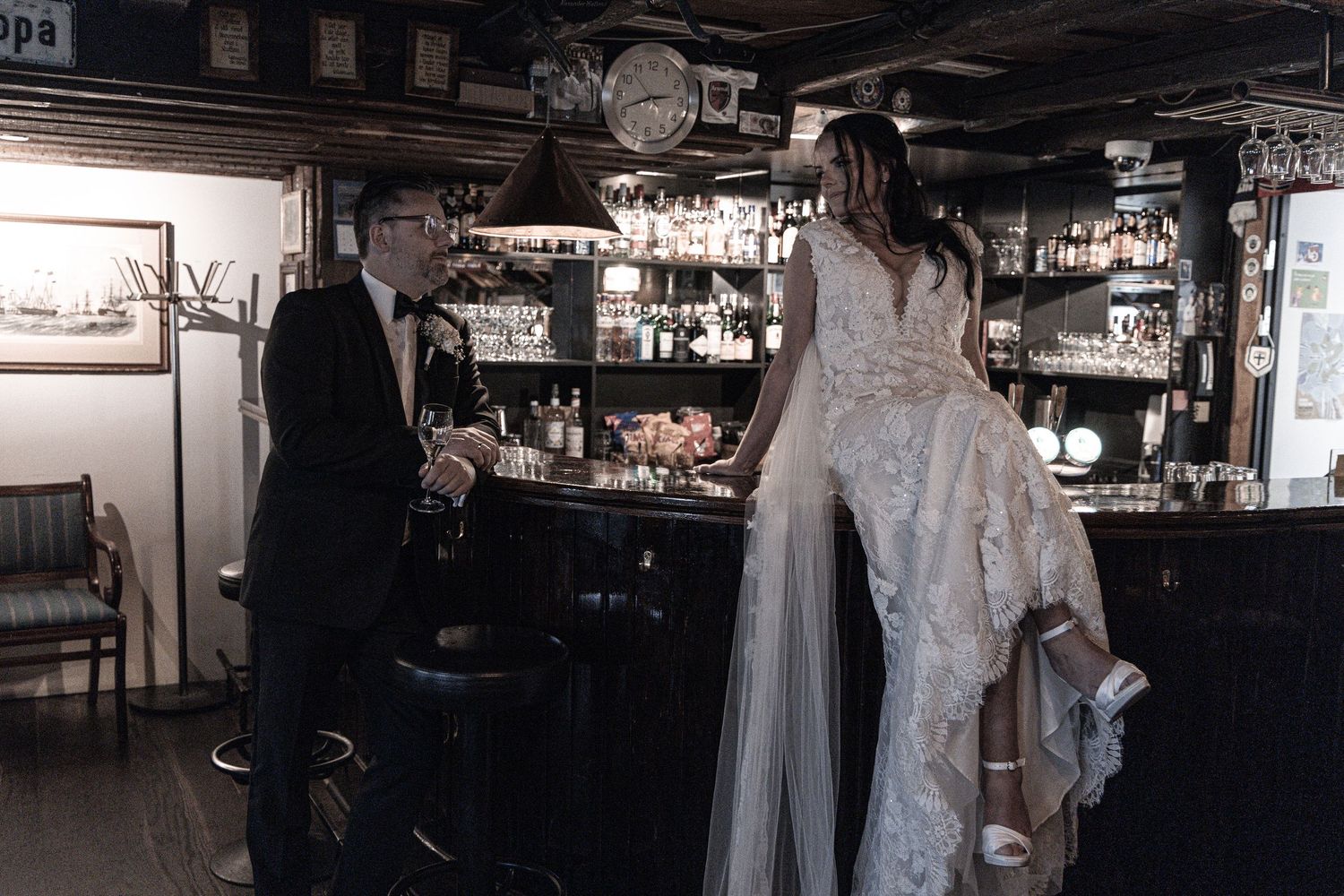 Bride and groom sharing a candid moment together at a vintage bar on their wedding day.