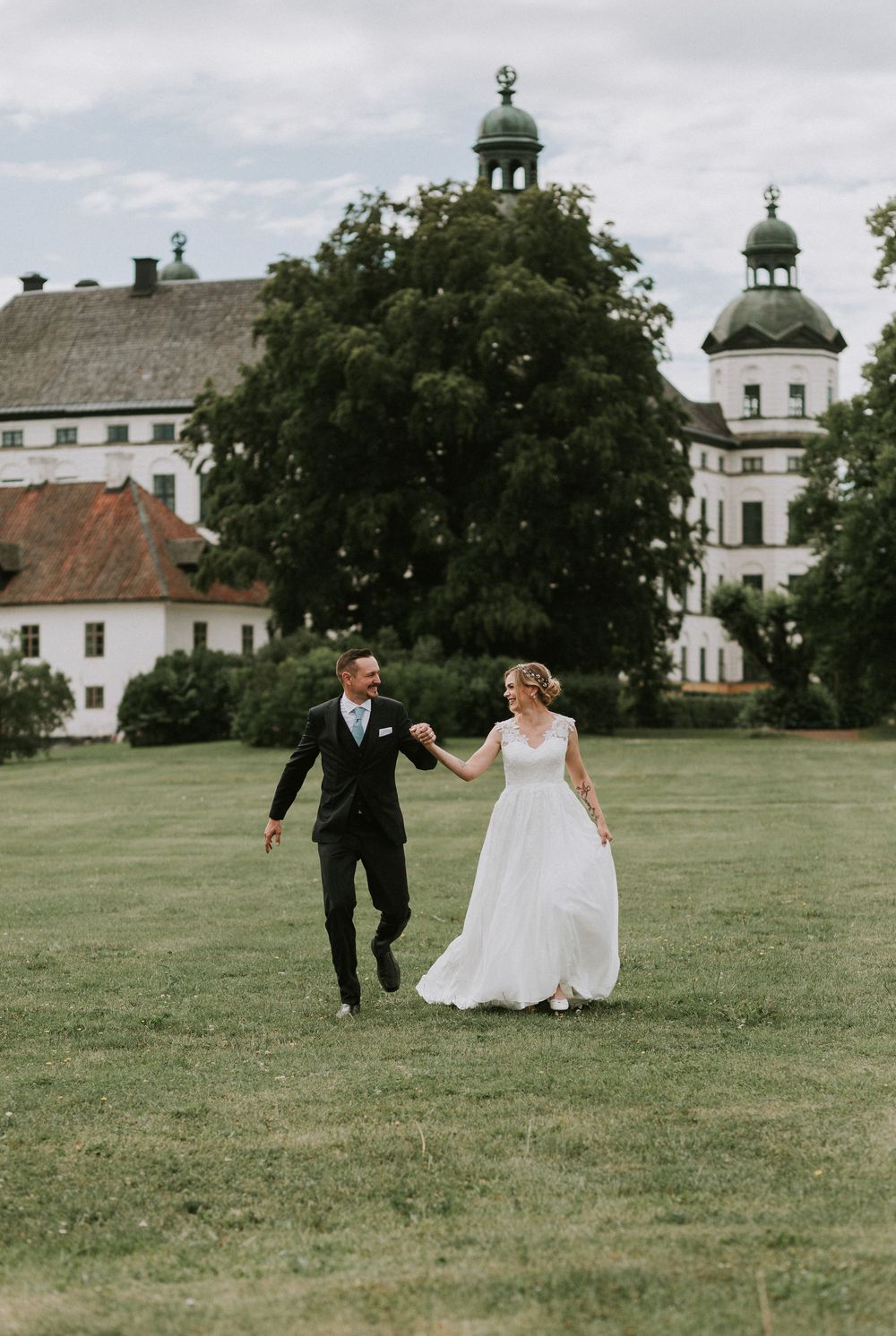 Brudpar porträtt vid Skokloster Slott med Mälaren i bakgrunden i varmt sommarljus