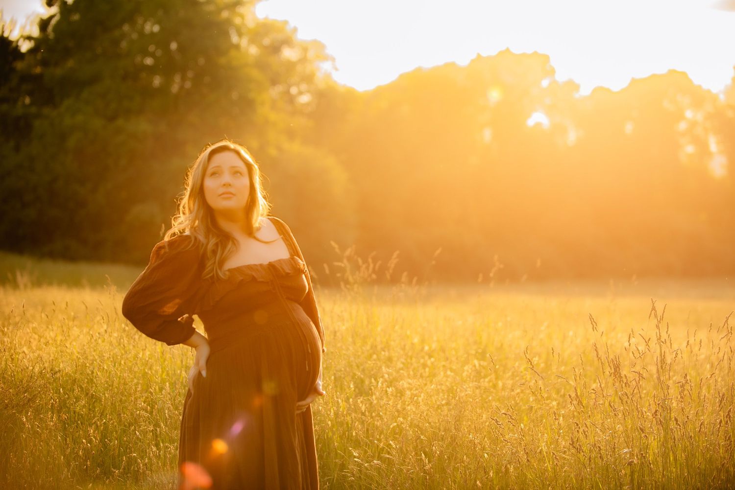 A portrait of a pregnant mama during her Maternity Photoshoot in a beautiful meadow with stunning light and light leaks.