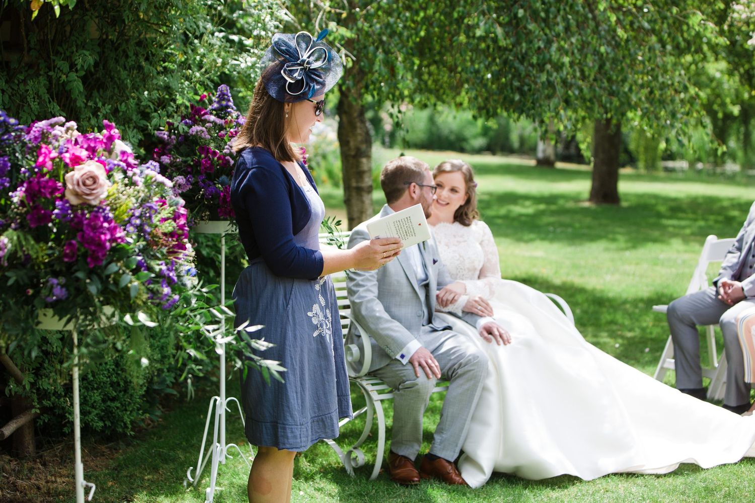 Bride in elegant lace wedding dress with long sleeves standing by a window in soft natural light.
