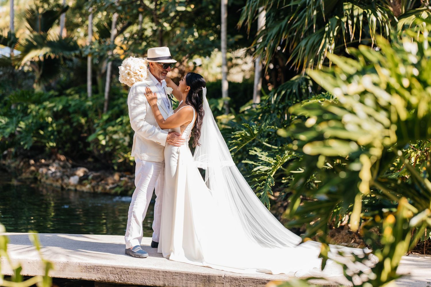 Romantic outdoor wedding ceremony with palm trees and flowing white veil.