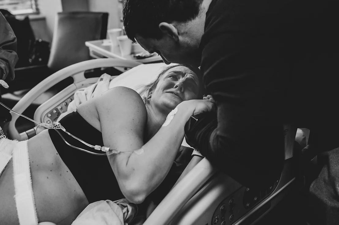 Black and white photo capturing an intense moment during labor in hospital setting.