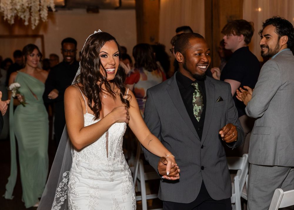 Joyful bride and groom laughing during their wedding reception entrance in a beautifully decorated ballroom.