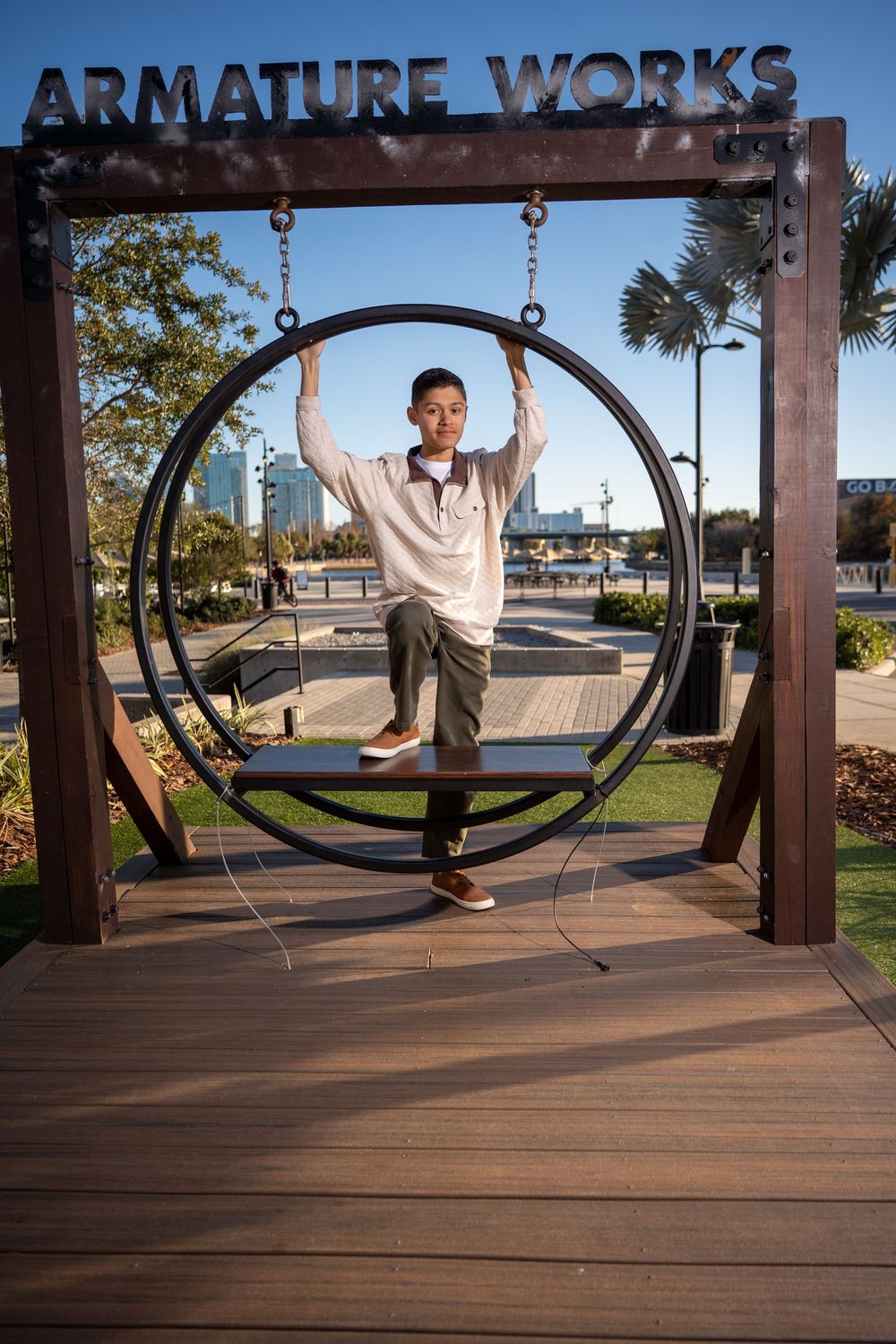 Boy poses inside a circular swing installation at Armature Works outdoor venue in Tampa, Florida on a sunny day.