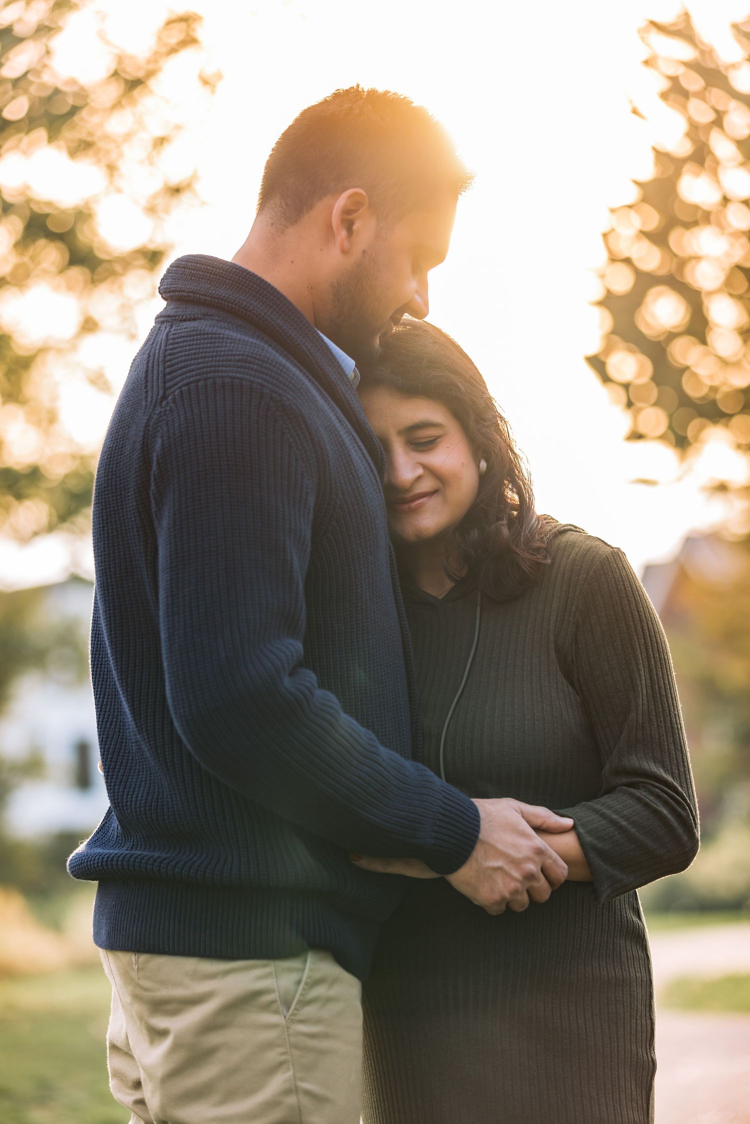 Indian couple sharing a heartfelt hug during a maternity photoshoot in Badhoevedorp at sunset
