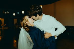 Bride and groom sharing a romantic kiss on the dance floor during their wedding reception.