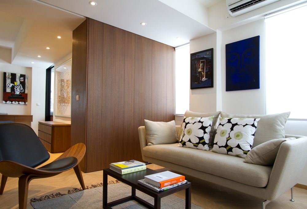 Contemporary living room with beige sofa, Marimekko cushions, walnut wall panel, and blue artwork.