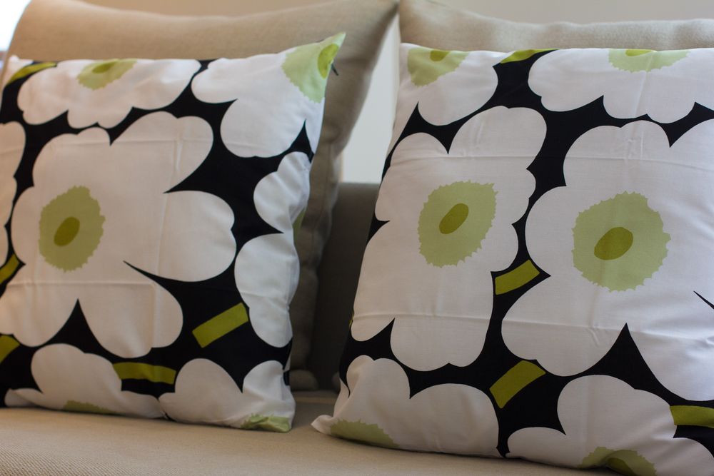 Close-up of decorative throw pillows featuring bold black and white Marimekko floral pattern with green accents.