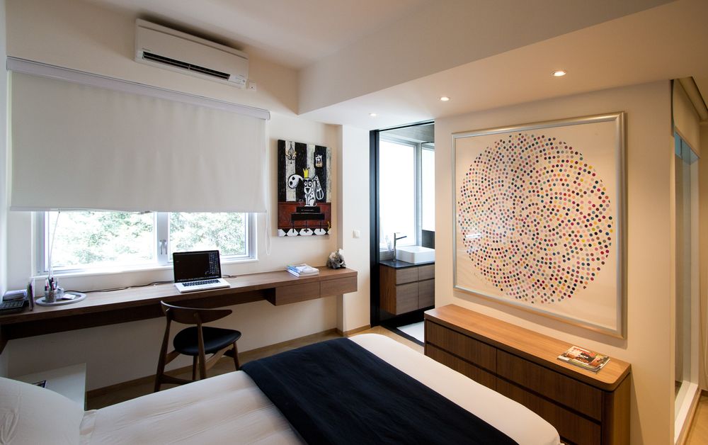 Modern bedroom with large circular dot wall art, wooden furniture, built-in desk by window, and wall-mounted AC unit.