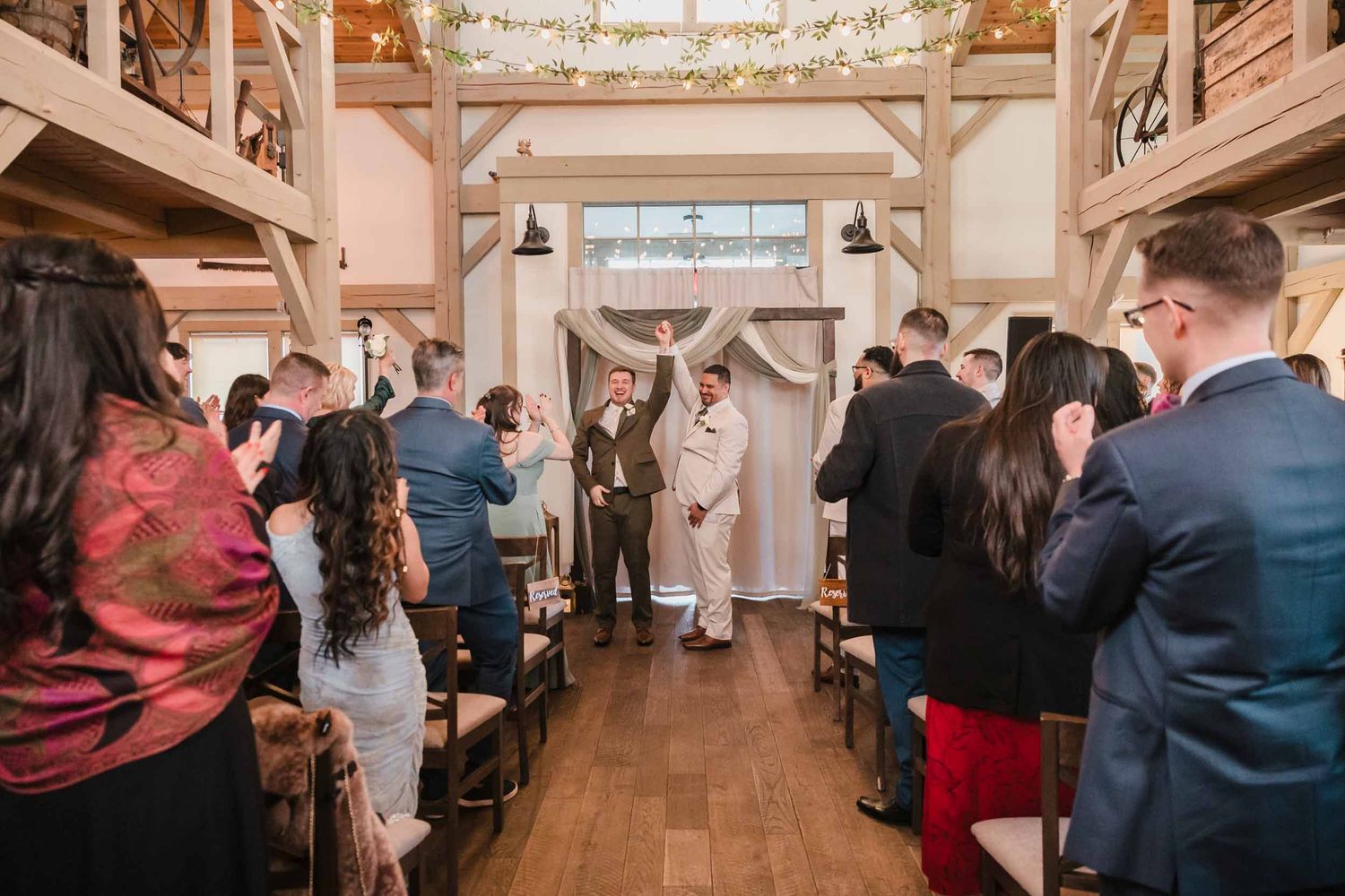 Couple celebrating and walking back down aisle after ceremony at Briar Barn Inn with guests applauding
