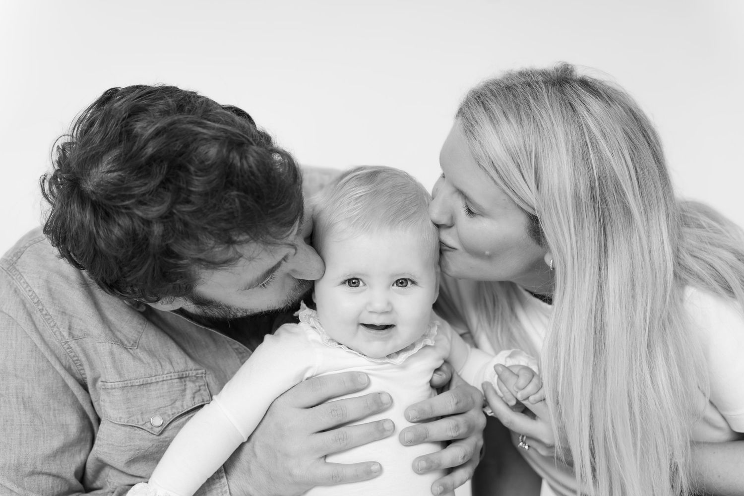 Family group wearing casual clothes sharing joyful moments together in bright studio.