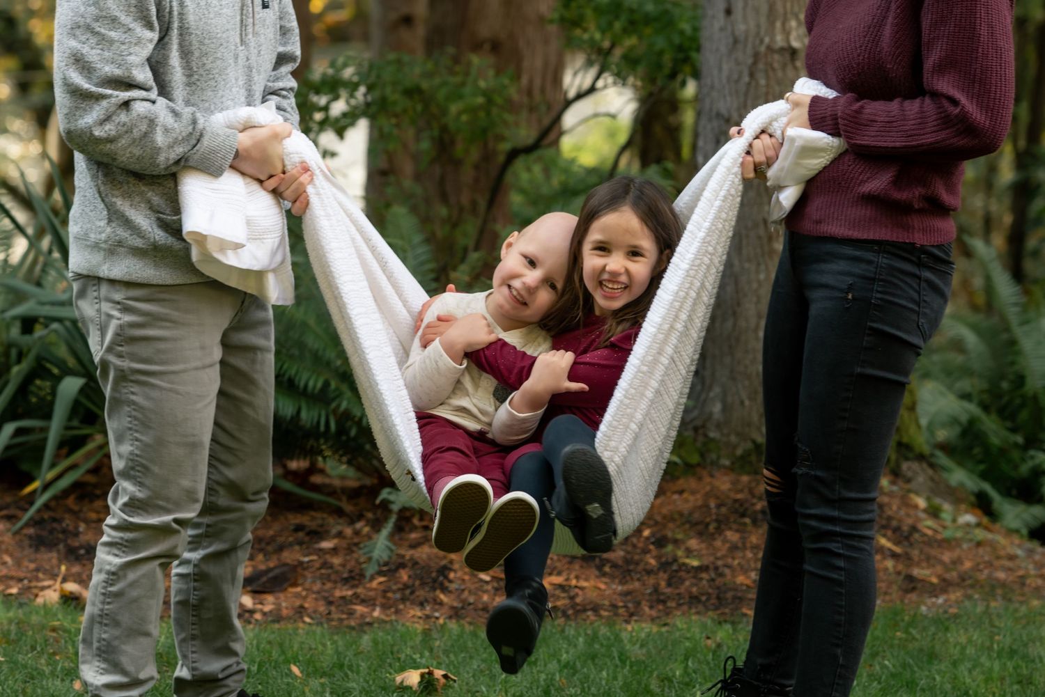 Family playing together with child in blanket swing outdoors.