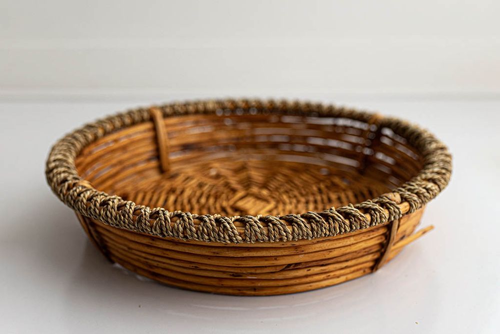 Round woven rattan basket on white backdrop.