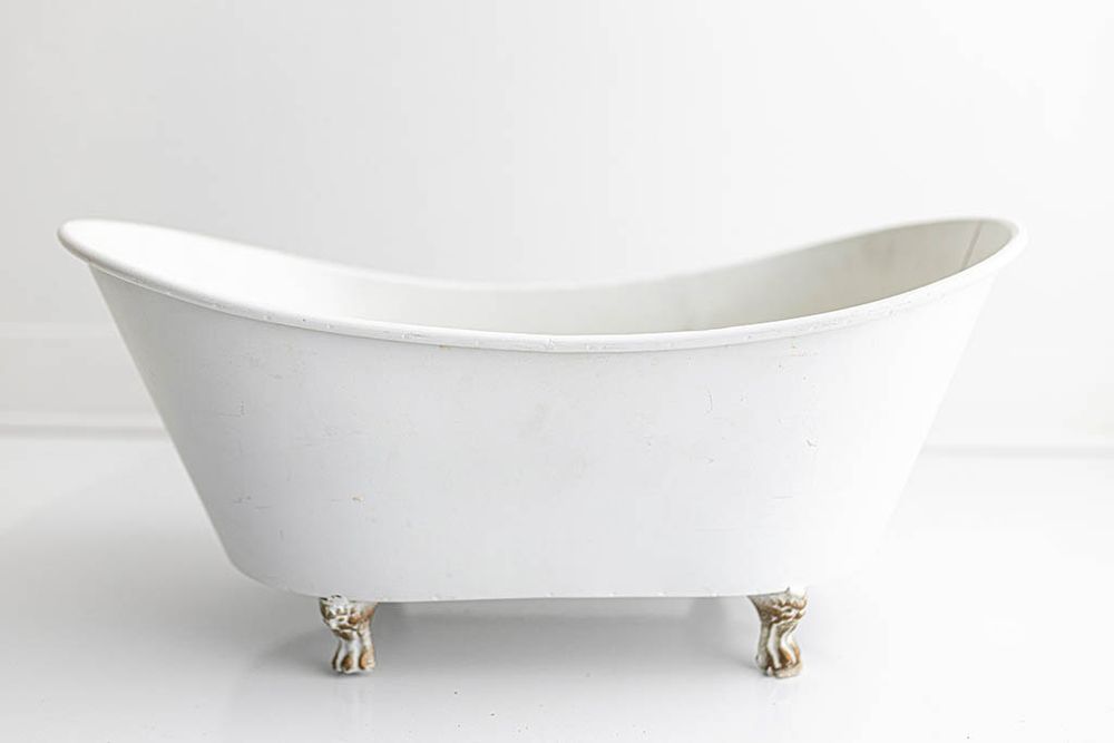 Elegant white clawfoot bathtub with gold lion paw feet on white background, baby studio photography prop.