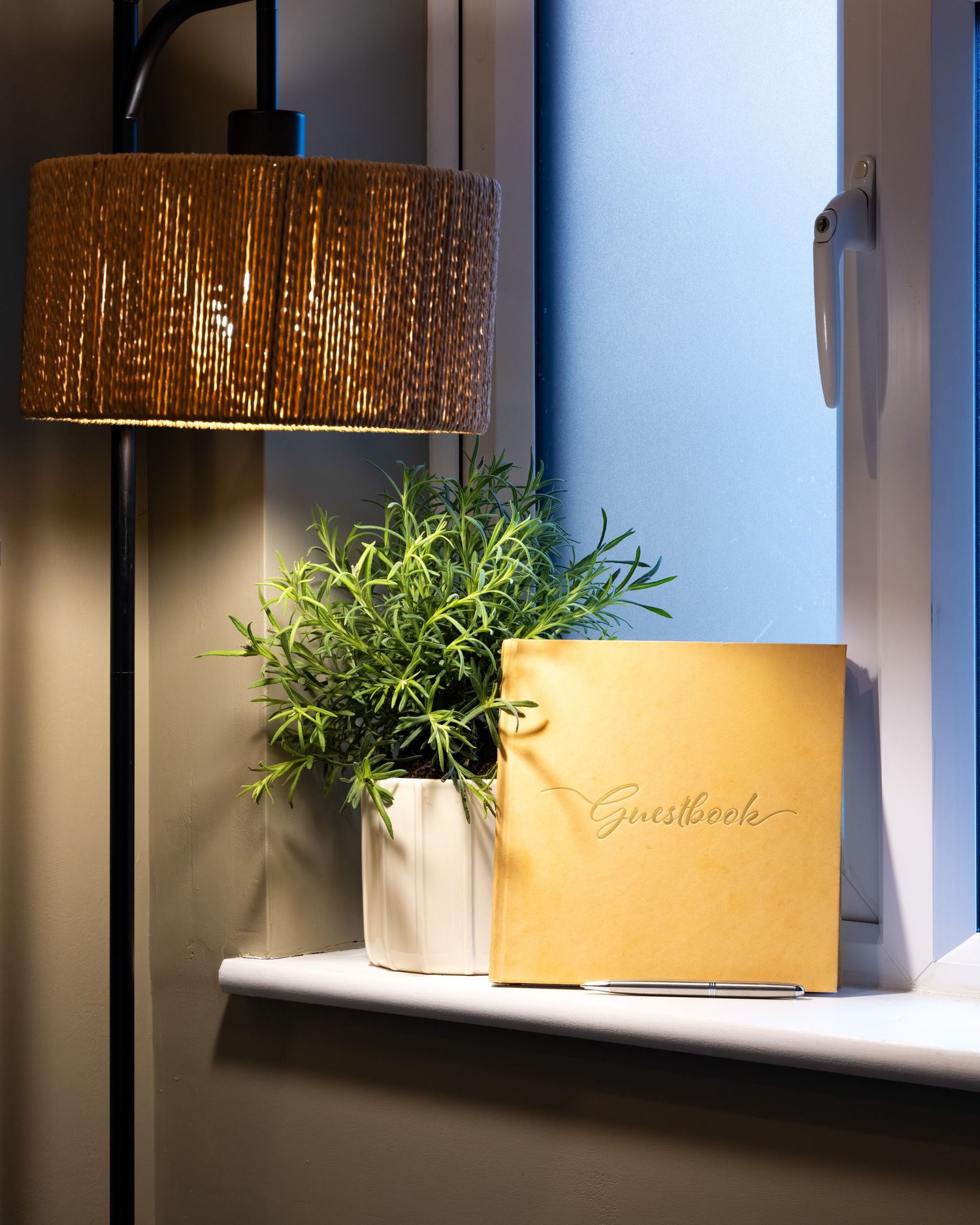 Spa interior detail in Bedfordshire with wicker lamp, plant and guestbook on shelf, part of an interiors shoot.