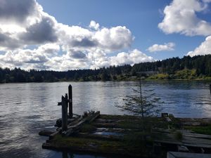 Wooden dock extending into a calm lake under a bright sky with scattered clouds