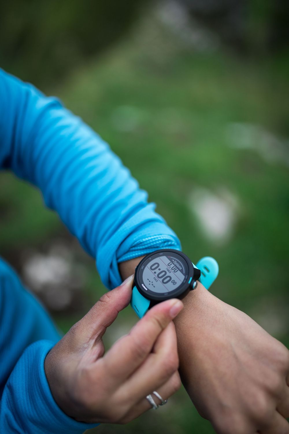 Person in blue athletic wear checking a GPS sports watch with timer displaying 0:00 outdoors.