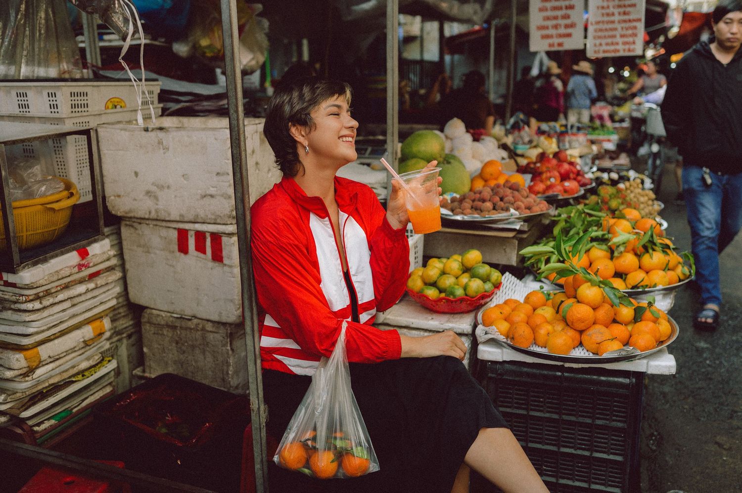 Model seated among fruit stalls at Banana Garden Market, Ho Chi Minh City — editorial lifestyle photography