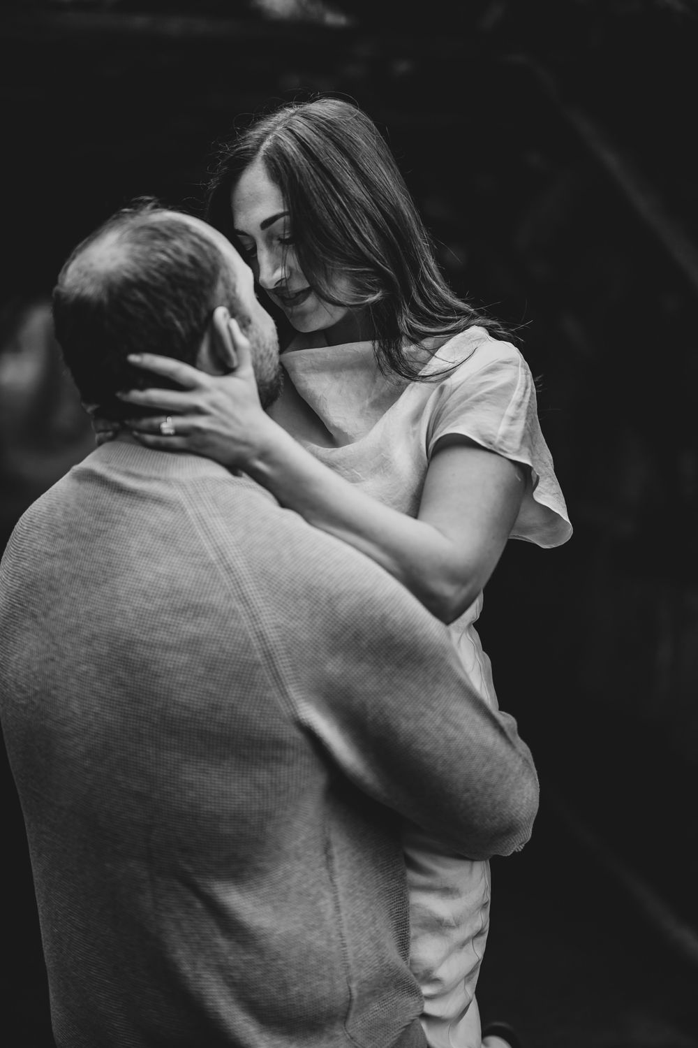 Black and white photo of a couple embracing tenderly, woman cradling mans face in an intimate moment.