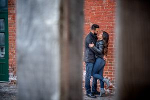 Romantic couple embracing in an urban alleyway framed by weathered wooden posts.