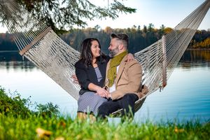 Couple sitting together in a hammock by a peaceful lake during golden autumn season.