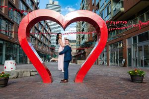 Couple posing inside iconic red heart art installation at Toronto distillery district plaza.
