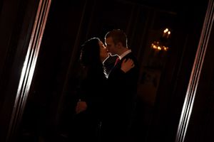 Couple sharing a romantic kiss in dramatic dark lighting at an elegant indoor venue.