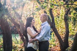 Couple sharing a tender moment surrounded by colorful autumn foliage in a sunlit park.