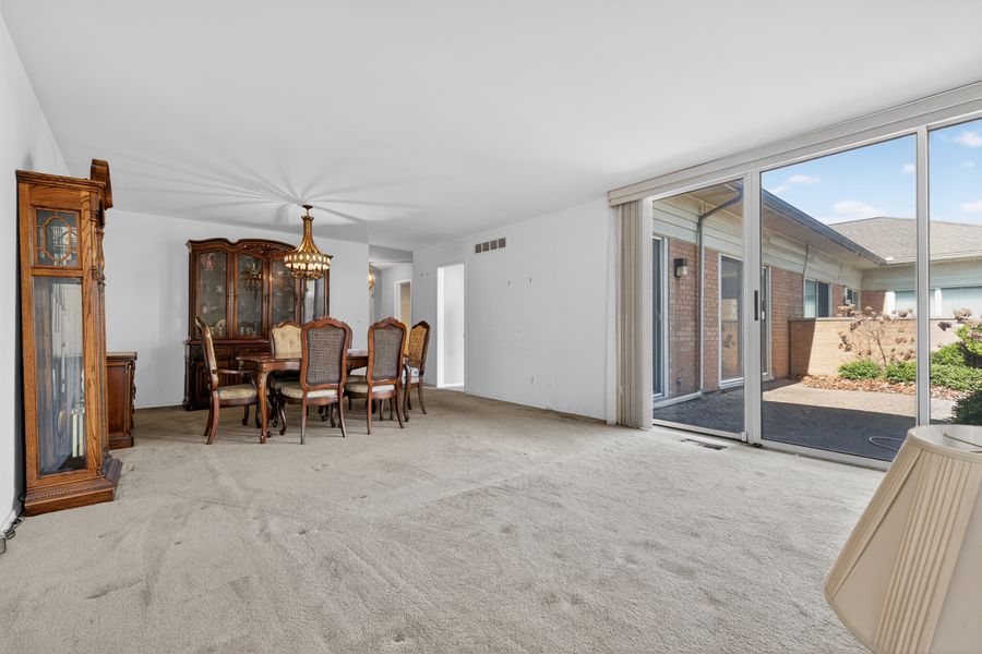 Spacious dining room with wooden furniture, ceiling fan, carpet flooring, and large sliding glass doors.