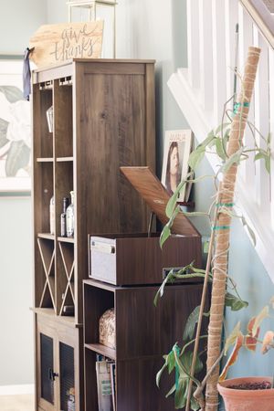 Dark wood bookshelf with decorative items, plants, and a give thanks sign near a staircase.