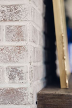 Close-up of whitewashed brick fireplace surround with rustic wood mantel detail.