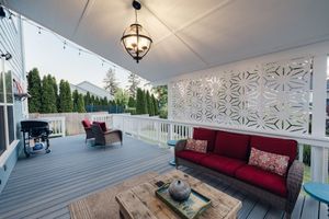 Spacious outdoor deck with red sofa, string lights, decorative screen, and pendant light.
