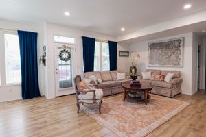 Tri-Cities senior photographer. Bright living room with hardwood floors, beige sofas, navy curtains, and a decorative rug.