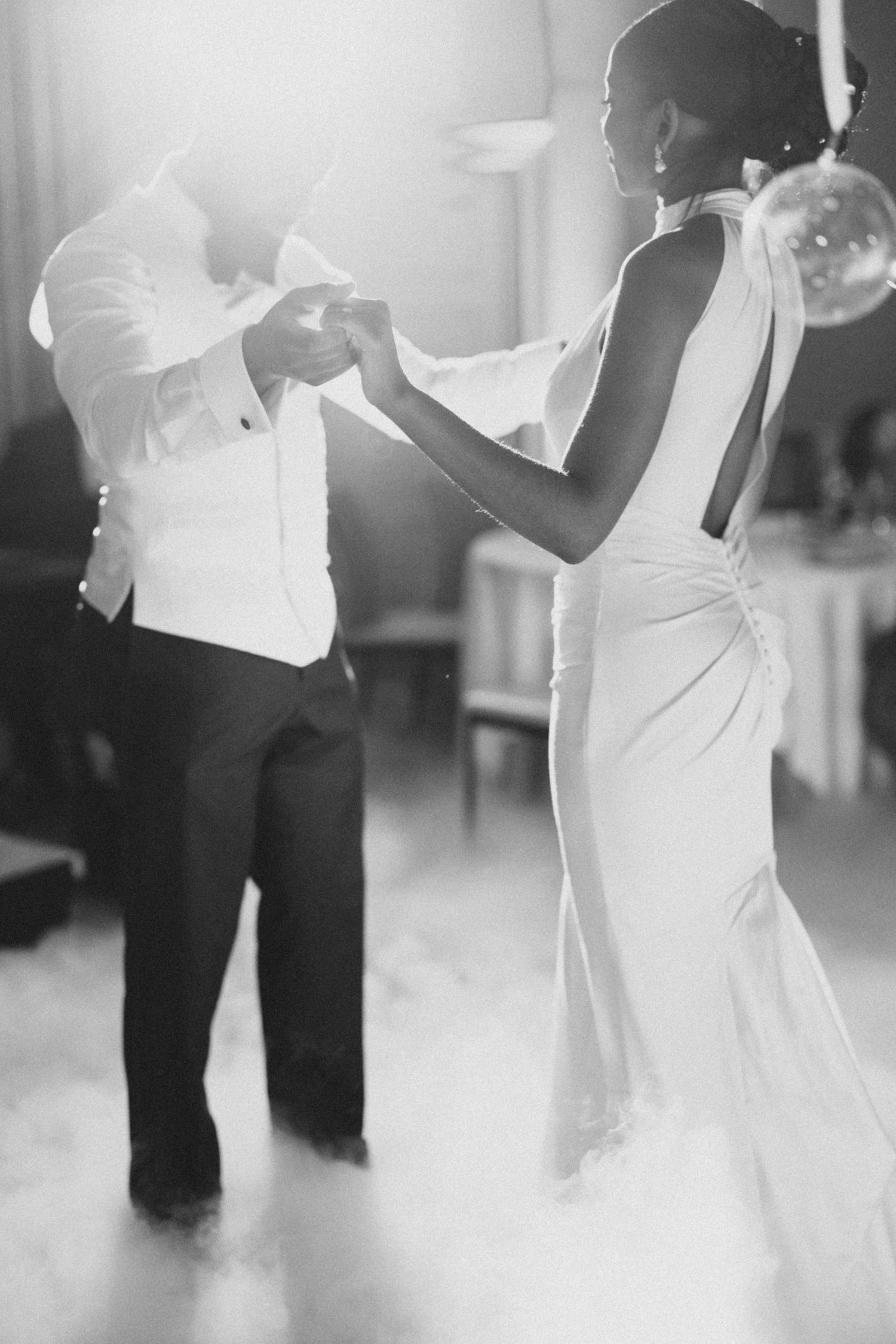 A black and white photo of a couple dancing in formal attire at their wedding reception.