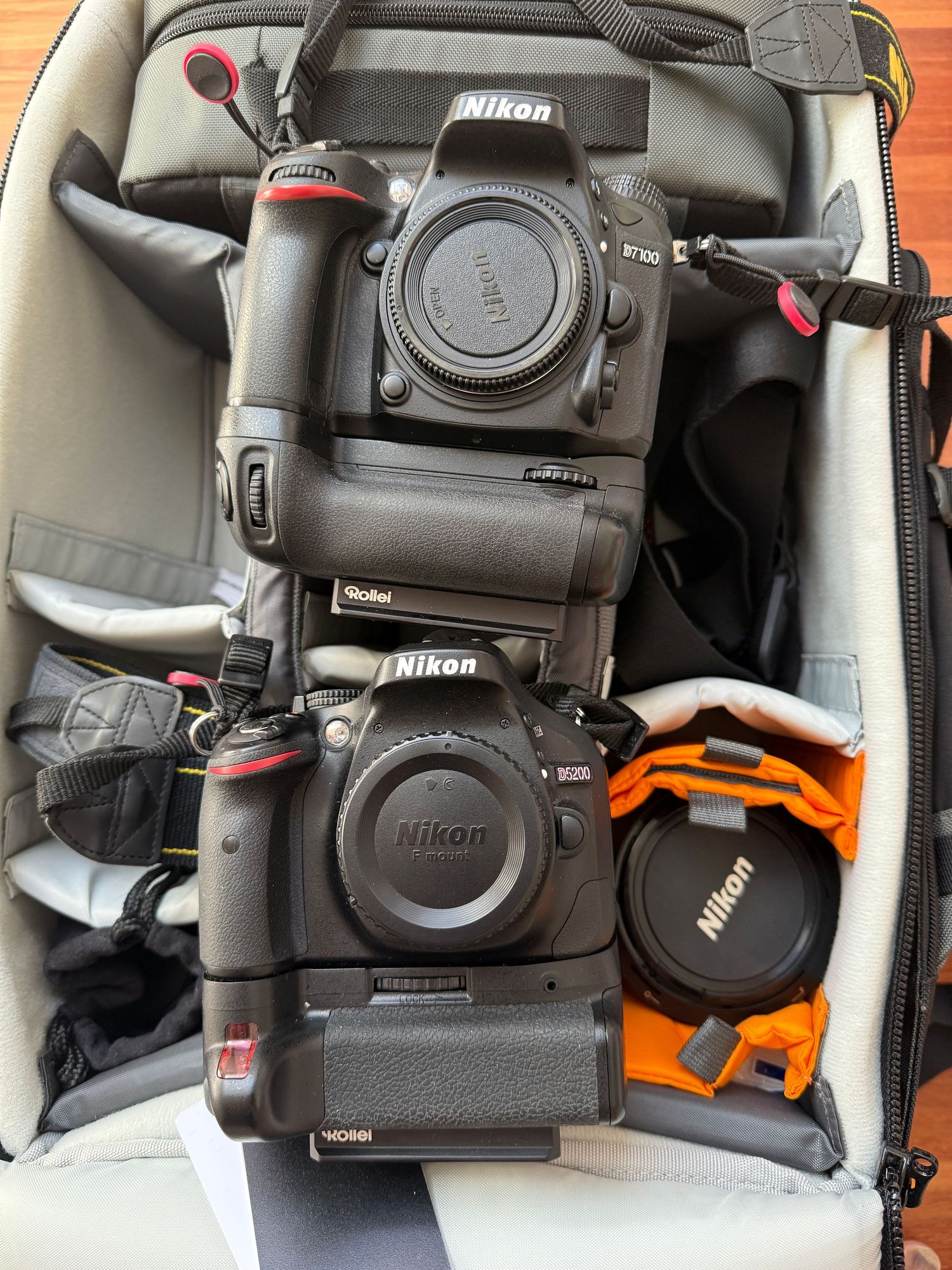Two Nikon DSLR cameras with battery grips stored in a camera bag.