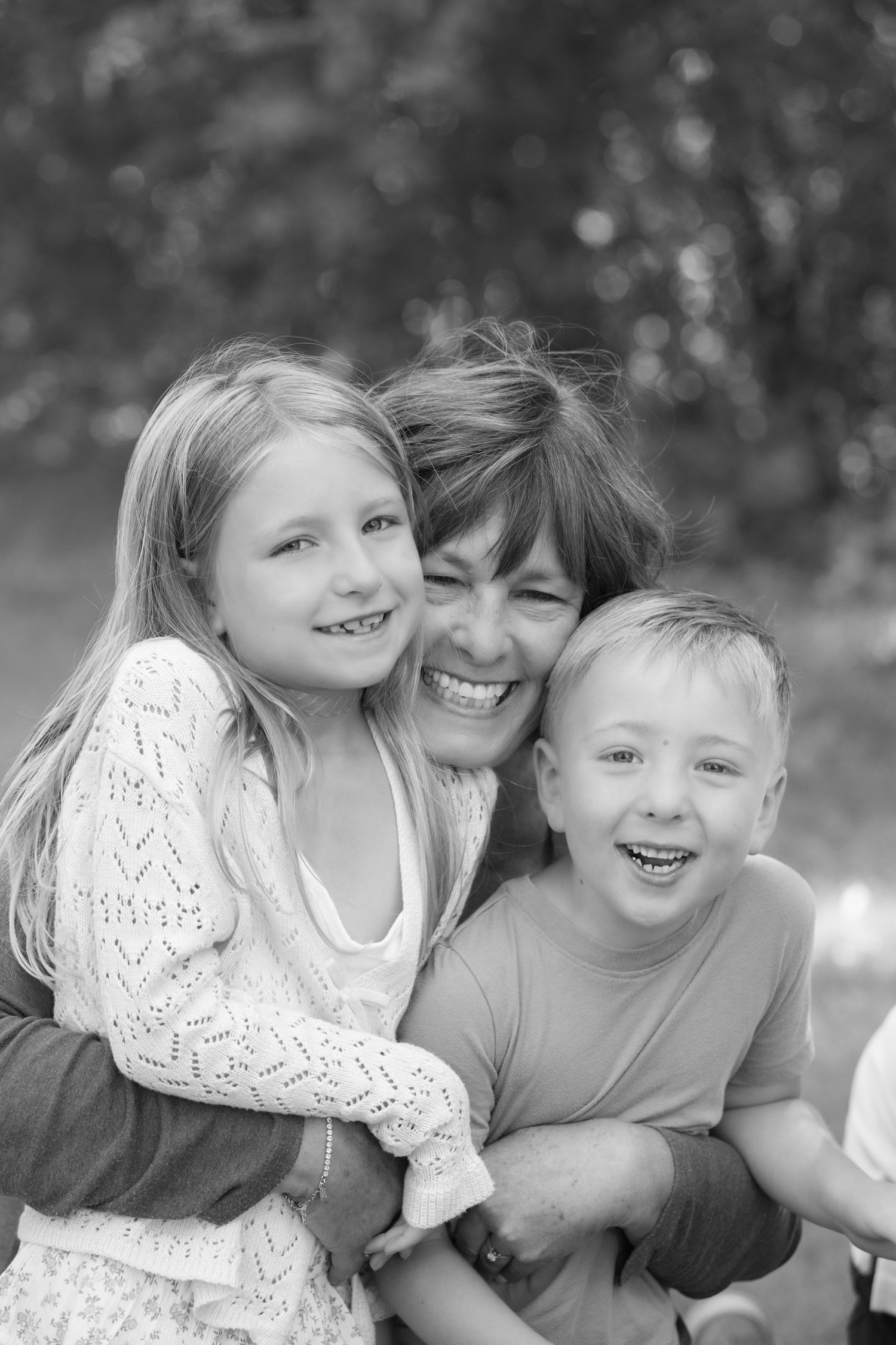 black and white closeup of grandma snuggling two of her grandchildren during extended family portrait session at powers lake park in MN