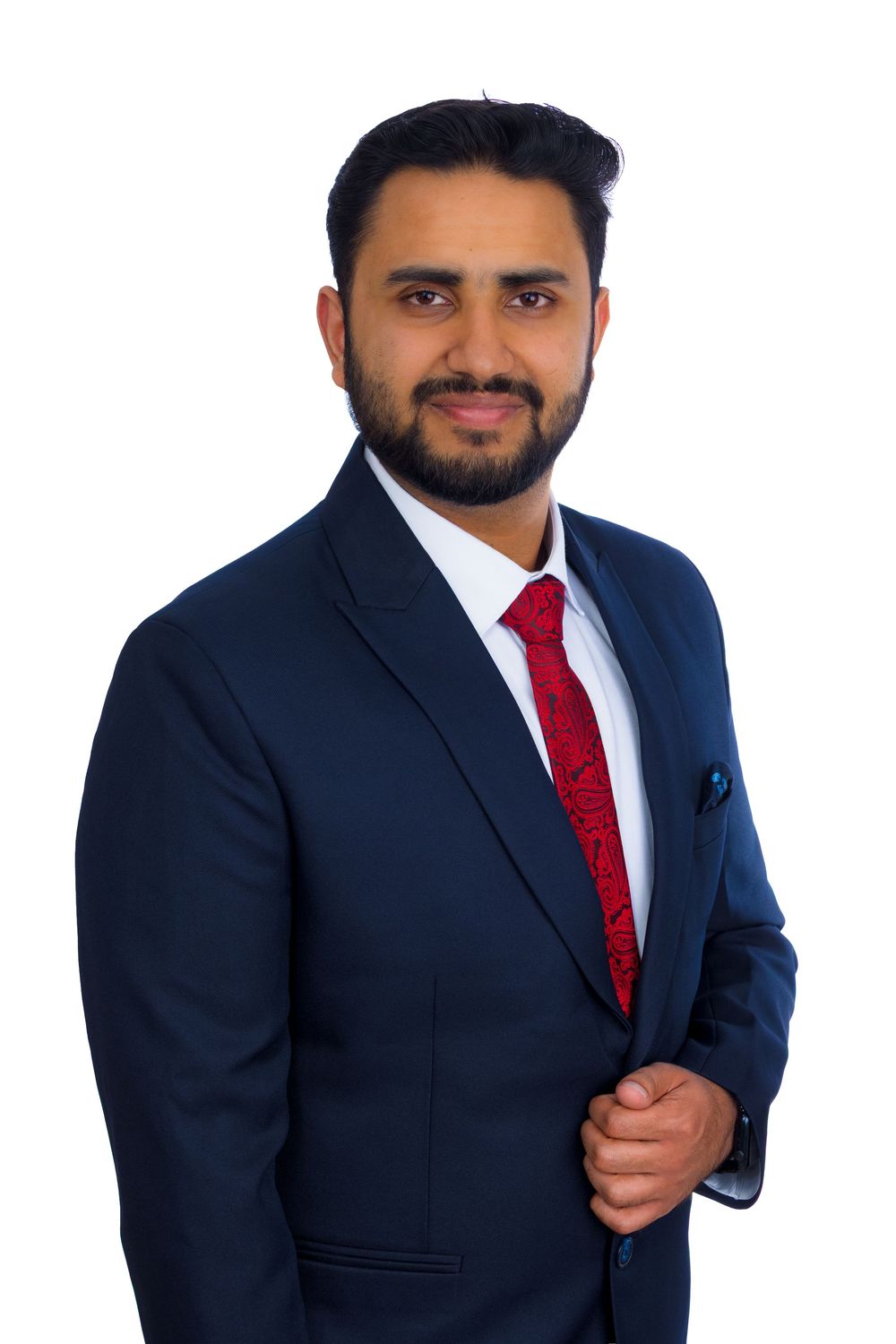 Professional man in navy blue suit and red tie smiling against white background.