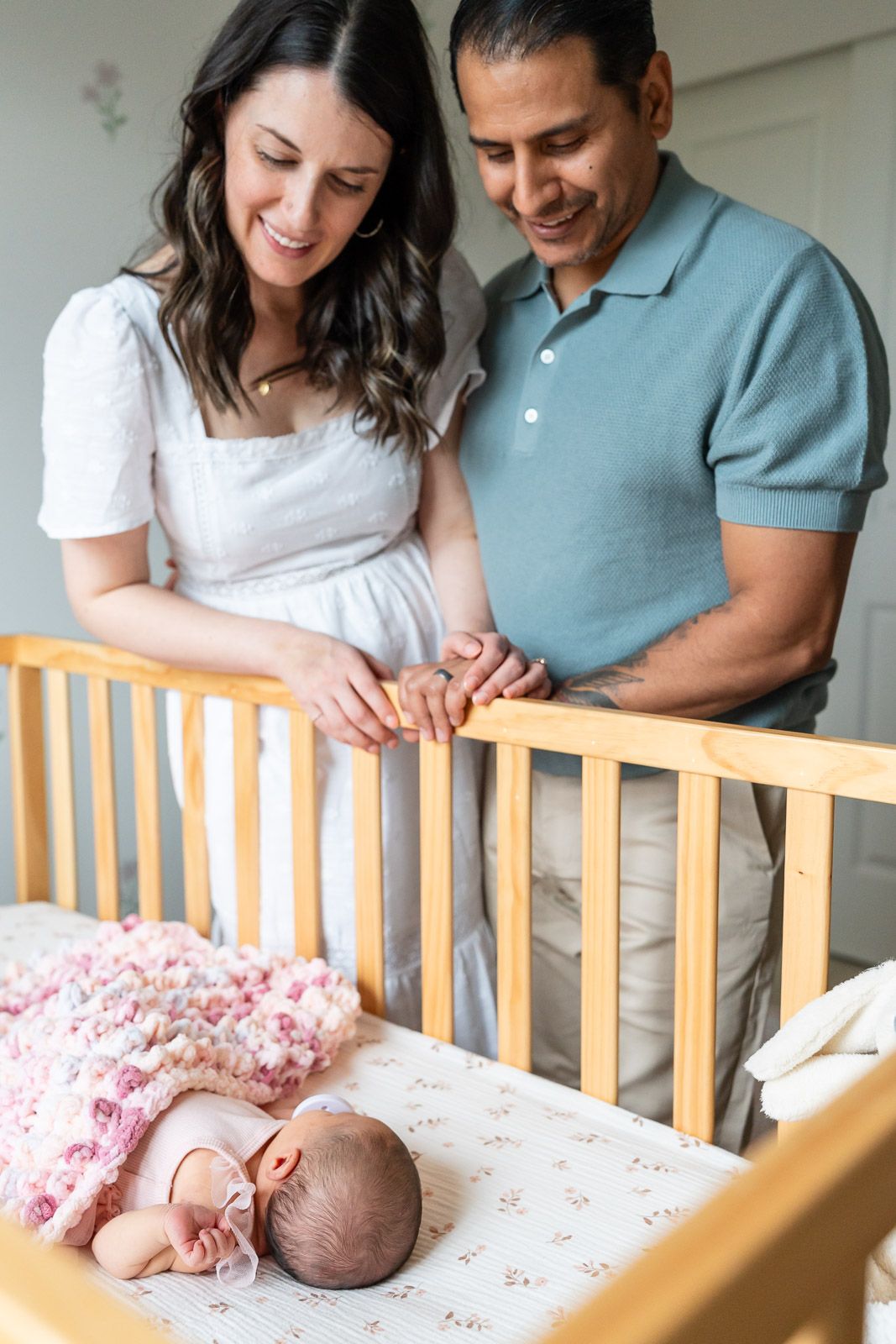 Parents admiring sleeping baby in crib in Seattle.