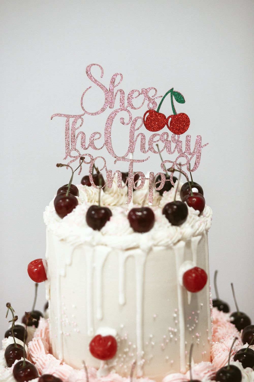 Two tier cake with topper on the pink dessert table at a miami baby shower. It's a girl!