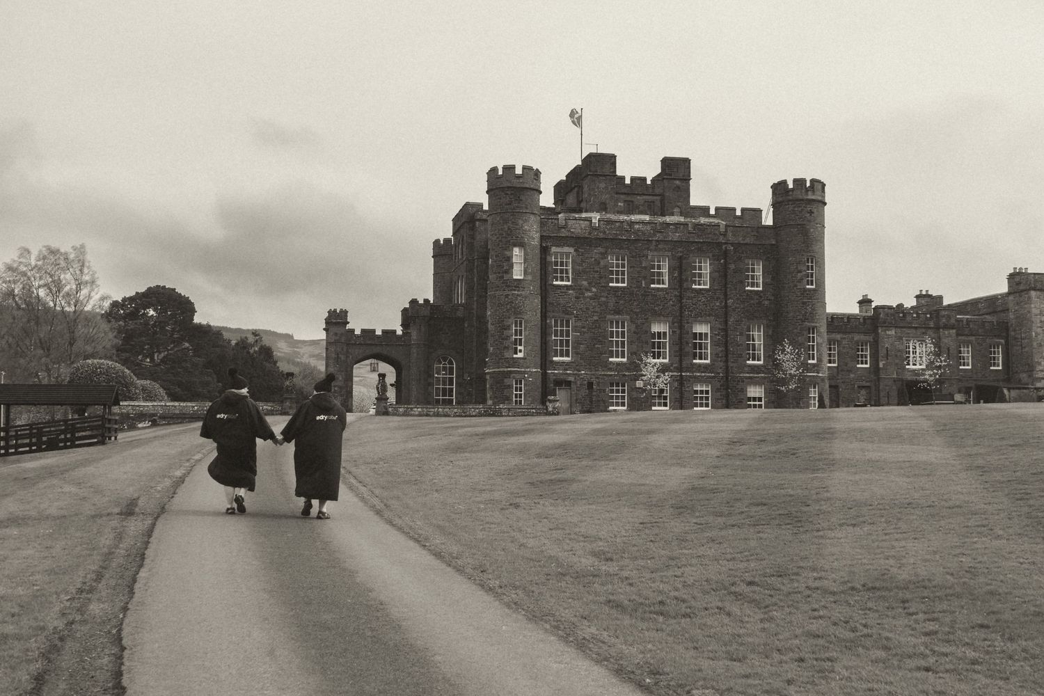 Couple walking towards Stobo Castle in a moody black and white portrait after their intimate Scotland wedding.