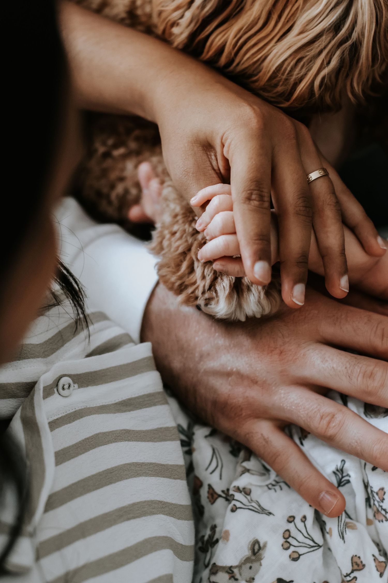 A newborn baby lying on a white blanket outdoors, with tiny feet raised in the air against a blurred green background.
