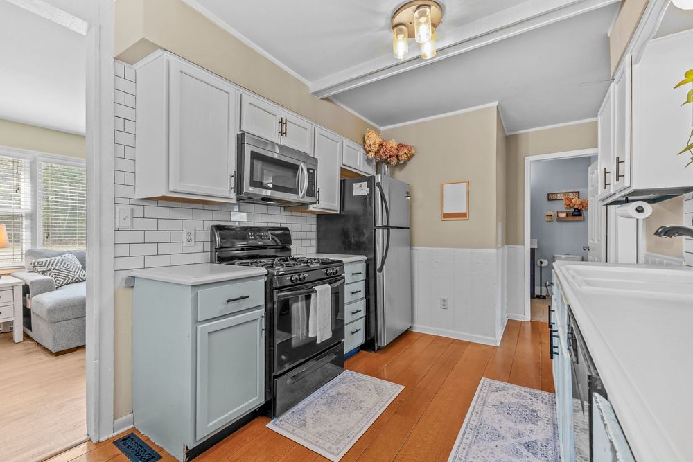 Modern kitchen with light blue cabinets, stainless steel appliances, and subway tile backsplash.