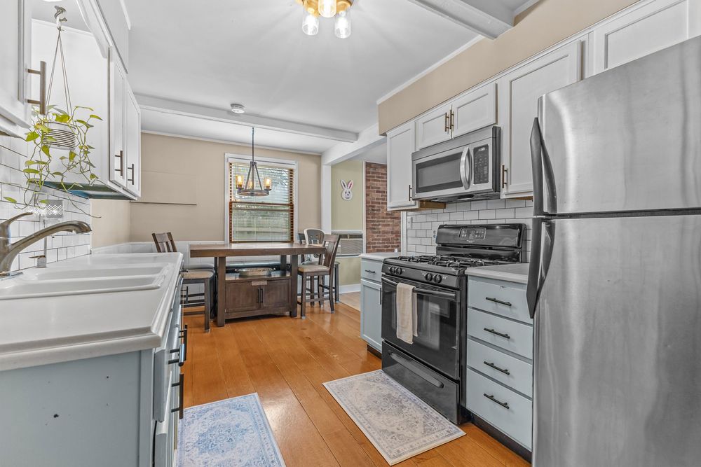 Open kitchen with light blue cabinets, stainless steel appliances, and view into dining area.
