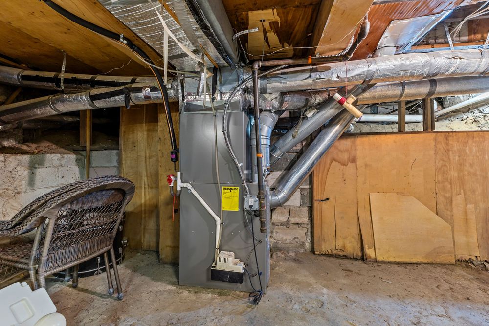 Unfinished basement utility area featuring a furnace with ductwork and exposed wooden beams.