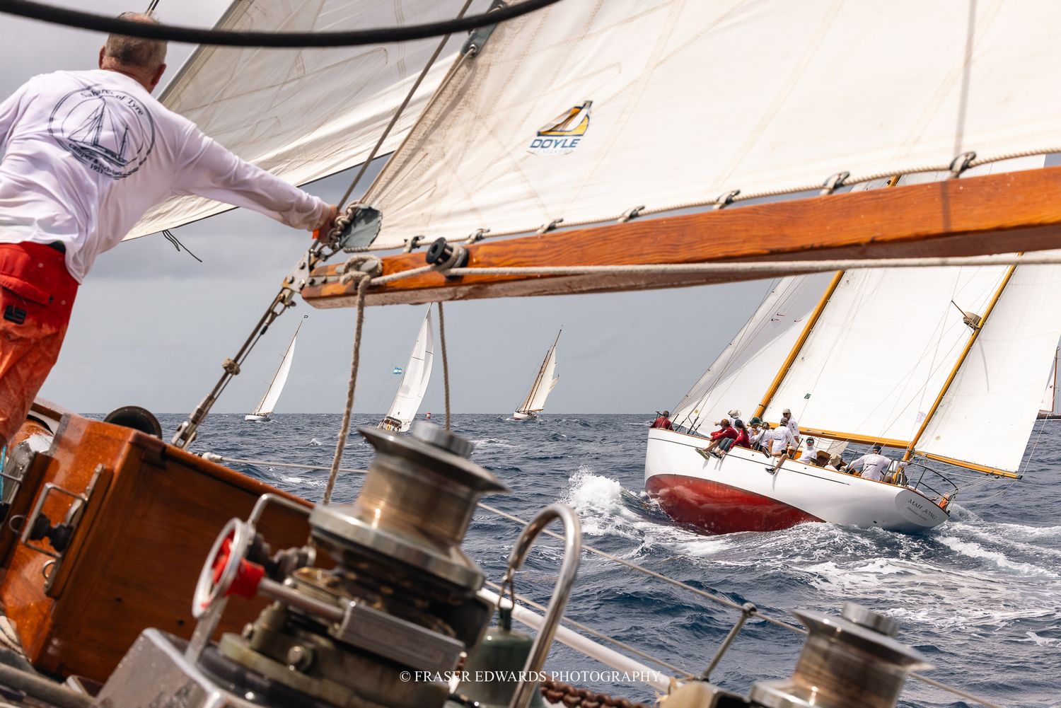 Classic wooden sailboats racing on choppy seas, crew on deck managing rigging during a competitive offshore sailing regatta.