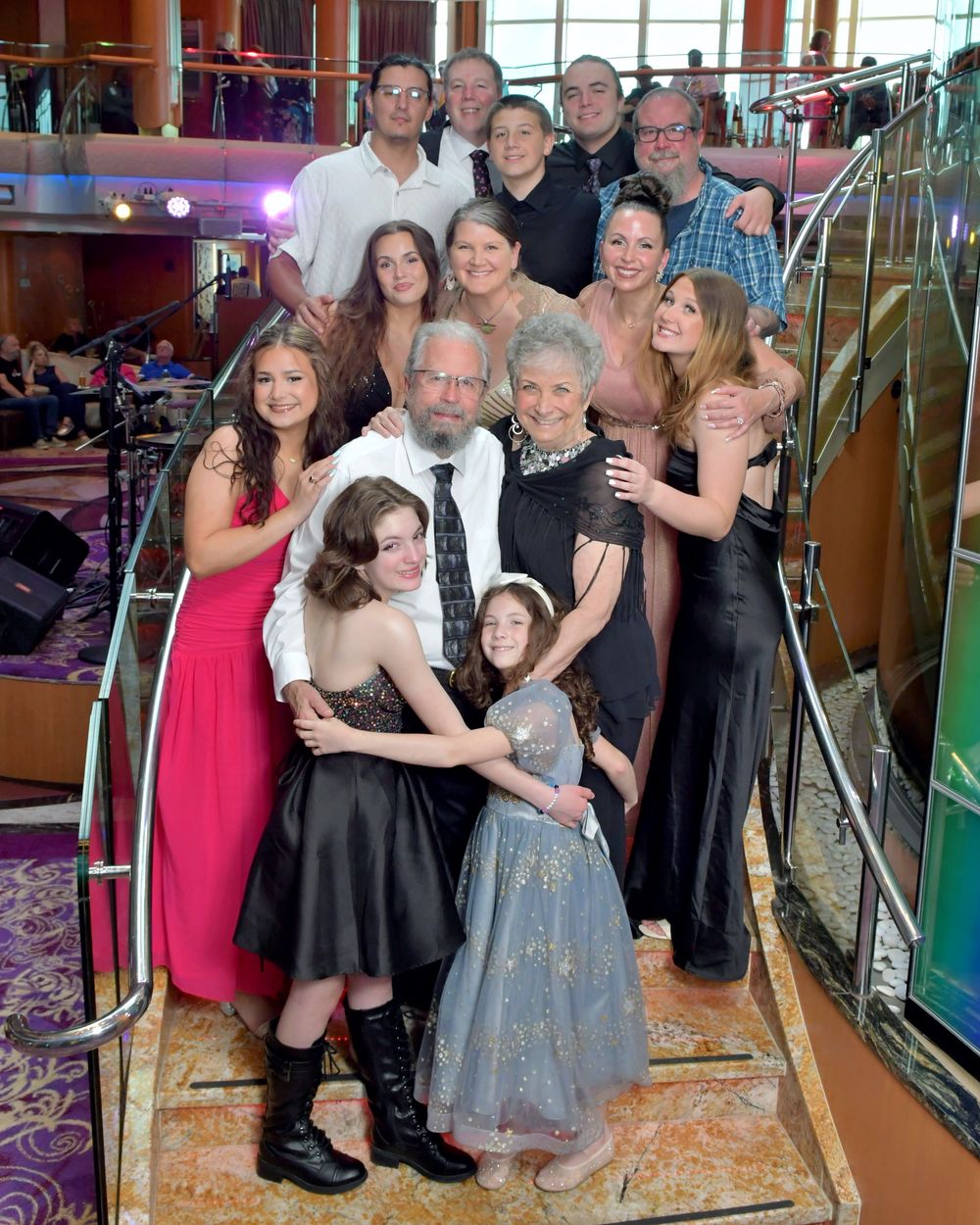 Large family group photo on cruise ship staircase, spanning multiple generations in formal attire.