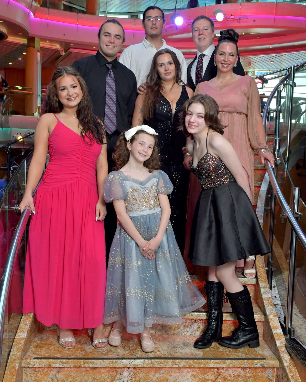 A family of seven poses formally on cruise ship stairs in elegant evening attire.